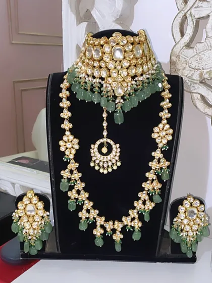 A full view of the green beaded Kundan bridal set on a display bust. This rental set includes the choker, long necklace, earrings, and maang tikka.