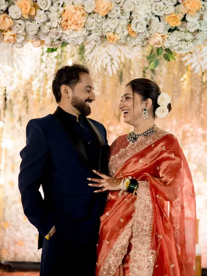 The couple shares a joyful moment at their reception. The bride's makeup is elegant and glowing.