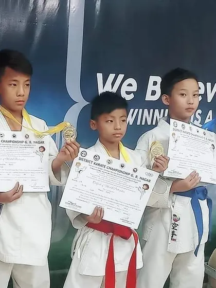 The journey to the top begins here. Our junior fighters proudly displaying their medals and certificates from the District Karate Championship, the first step on the competitive ladder.