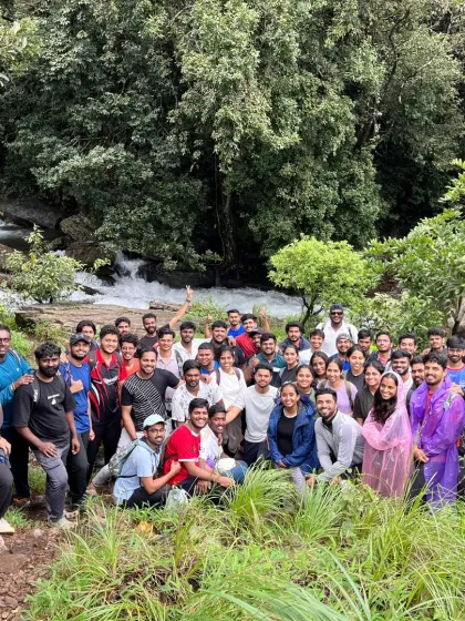A large group enjoying a break by a small waterfall. These spots are perfect for a quick refresh during the trek.