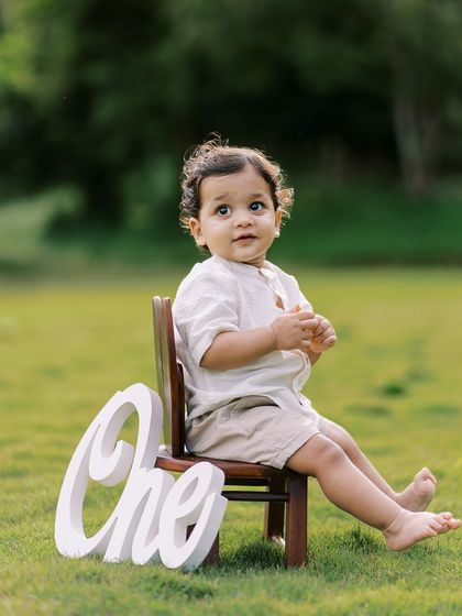A classic portrait of a one-year-old with a "One" sign. Simple, timeless, and perfect for remembering this milestone.