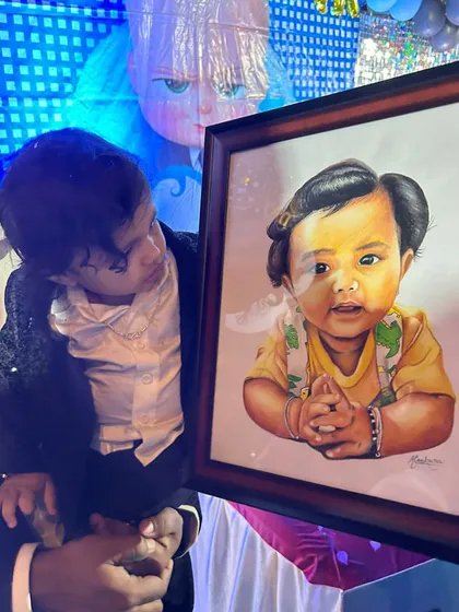 The baby from the portrait looking at his own sketch. This is the most rewarding part of my job, seeing the joy my art brings.