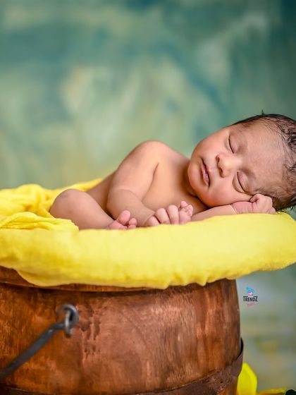 A close-up of the newborn in the bucket, focusing on their peaceful, sleeping face.