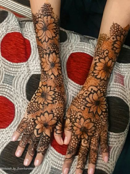 An intricate floral henna design with large, beautiful flowers covering the hands.