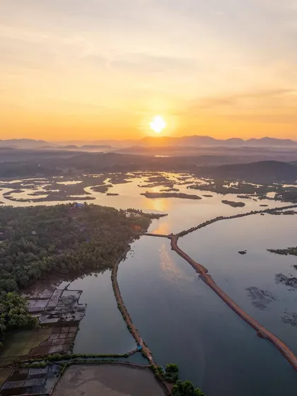 A golden sunrise over the Aghanashini river in Kumta. This high-angle aerial shot captures the light hitting the water and the distant hills, showcasing the beauty of the Uttara Kannada region.