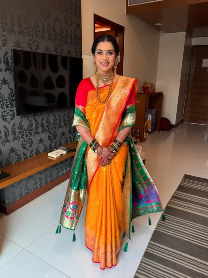 A full-length view of a stunning Maharashtrian bride. Her hair is elegantly styled to support her dupatta, and the makeup is designed to be flawless both in person and in photographs.