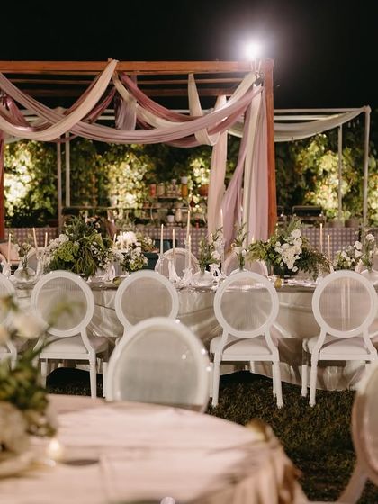 A wide shot of the elegant dinner party in Goa, with draped cabanas and beautiful table settings.