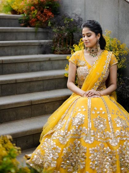 A wide shot showing the entire look in a beautiful setting. The bride looks like a vision in her yellow lehenga and flawless makeup.