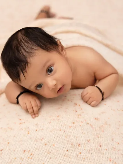 Capturing the early days with a simple and clean aesthetic. This baby's alert expression and soft skin are the focus, with a neutral blanket providing a gentle and uncluttered background.