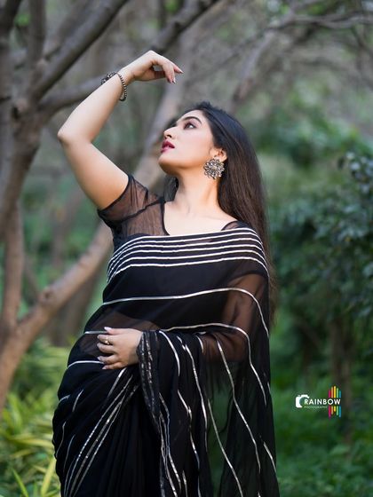 A graceful pose in a black striped saree, with the model looking up, creating an elegant and artistic shot.