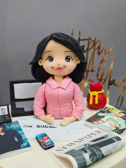 A last-minute cake for a PR expert, featuring a figurine at her desk surrounded by newspapers, magazines, and a phone. I thrive on the rush of bringing these professional themes to life.