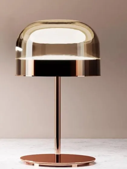 A classy table lamp with a copper finish and a smoked glass dome shade. The sleek, modern design is perfect for a desk, side table, or nightstand, providing stylish and functional task lighting.