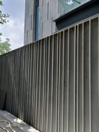A wider view of the fluted stone boundary wall, showing its relationship to the main building in the background. This illustrates how we design all elements on a property, from the main structure to the boundary, to create a unified architectural statement.