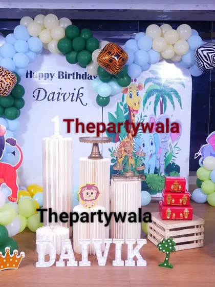 A jungle theme with a blue and green balloon arch. The setup includes cutouts of a lion, deer, and elephant, perfect for a little animal lover.