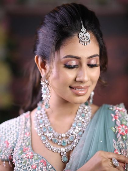 A serene, eyes-closed pose that highlights the delicate maang tikka and the layers of the necklace.