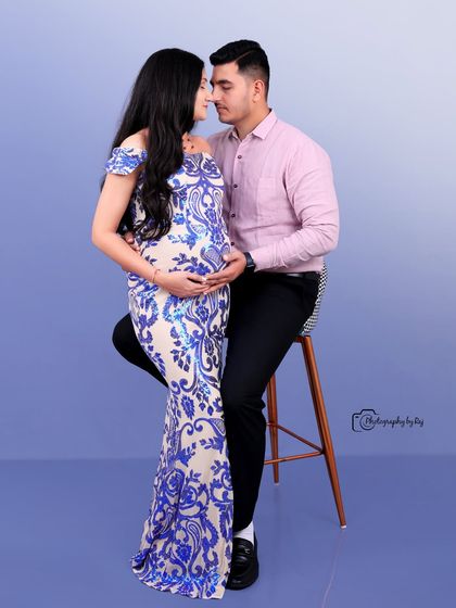 A glamorous studio portrait of a couple, with the mother-to-be in a blue and white sequined gown.