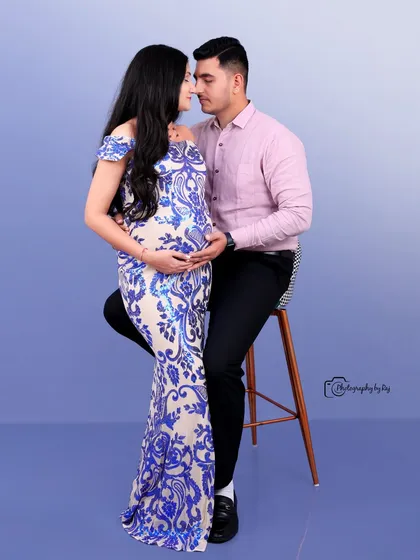 A glamorous studio portrait of a couple, with the mother-to-be in a blue and white sequined gown.