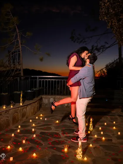 An intimate moment captured on a terrace surrounded by candles, with the twilight sky painting a perfect romantic backdrop. These carefully planned evening shoots create a magical atmosphere.