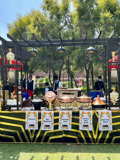 An elaborate buffet setup for a Holi celebration on a lush green lawn. The station featured a variety of main courses like Dal Makhani and Amritsari Chole, beautifully presented.