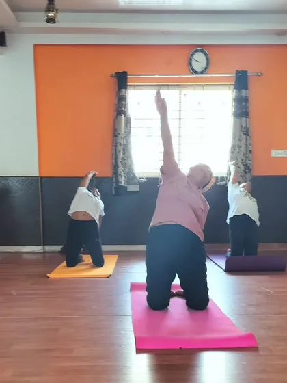 Students practicing a side-body stretch on their knees during a group session.