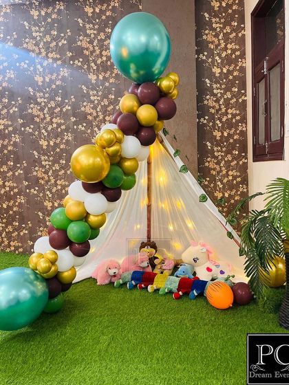 We created a cozy and playful kids' corner with a lighted teepee tent filled with stuffed animals. A balloon arch in jungle colors makes this a perfect little hideaway for the children at the party.