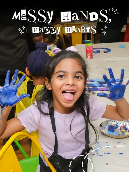 This is what pure joy looks like. At my kids' art parties, we embrace the mess because that's where the fun and creativity happen. This little artist is having a blast with paint-covered hands, showing off her colorful creations.