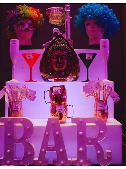 A quirky and fun bar setup featuring a Buddha head, colorful wigs on mannequins, and our illuminated "BAR" sign. We're not afraid to get creative and playful with our decor.