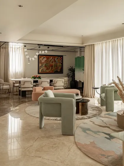 This open-plan living and dining area in a 5000 sq ft Kolkata home was designed for a family who wanted a soft, personal space. We used curved furniture in pastel greens and pinks, layered rugs, and polished marble floors to create a relaxed yet sophisticated feel.
