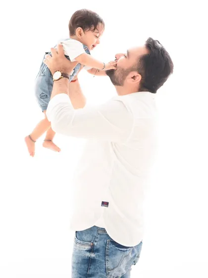 A moment of pure joy between father and child. This candid shot of a father lifting his baby in the air captures the playful spirit of family.
