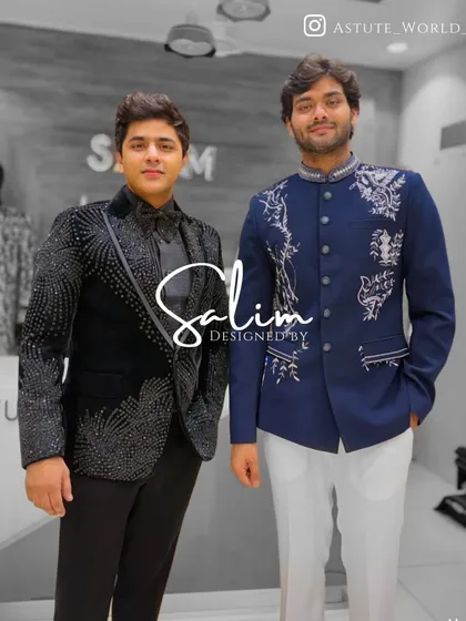 Two clients in contrasting styles. One wears a black tuxedo with cascading crystal work, while the other is in a blue Jodhpuri jacket with elegant white embroidery.
