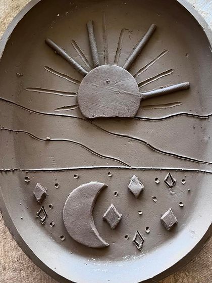 A close-up of the sun and moon trinket dish before glazing. I sculpted each element by hand to create a celestial design.