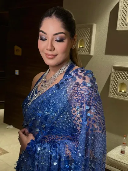 The bride in her sparkling blue saree, her high ponytail the perfect hairstyle for this modern ensemble.