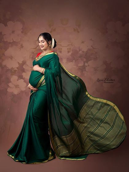 The elegance of a flowing green silk saree is timeless. This portrait, with its soft, painterly background, captures the grace and beauty of traditional Indian motherhood.