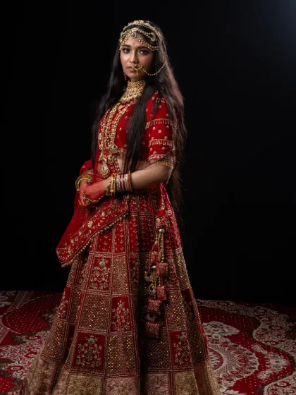 A full-length view of the royal Padmavathi lehenga. This rental costume is rich in detail, with heavy embroidery and luxurious fabric, set against a traditional rug in my studio.