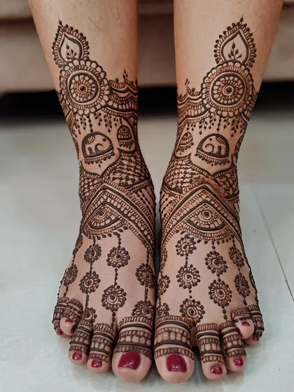 A beautiful foot design with hanging floral chains and small elephant figures near the ankle.