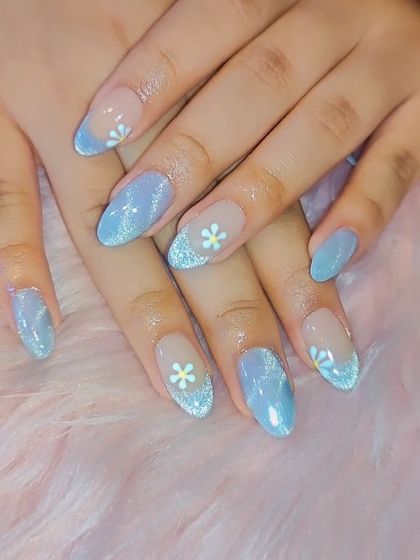 A dreamy, sky-blue glitter polish with a French-style tip. Accent nails are adorned with tiny, hand-painted white daisies for a sweet, summery vibe.