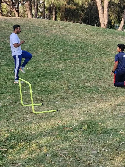 Setting up a hurdle drill on a grassy slope. Using varied terrain adds a different challenge and helps build more resilient athletes.