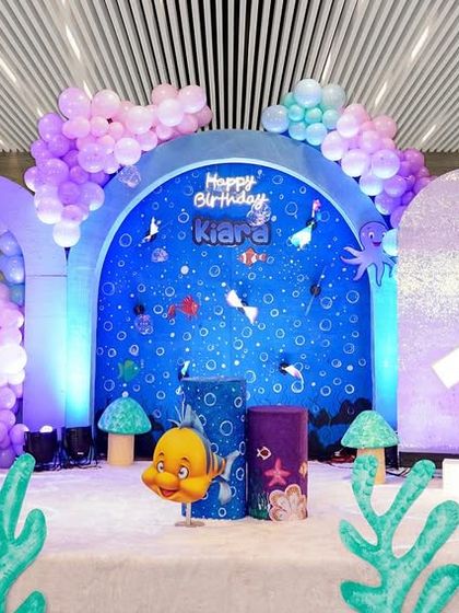 This is the design render for an "Under the Sea" mermaid party. It shows a beautiful setup with holographic backdrops, coral props, and characters from The Little Mermaid, all in a pastel color scheme.