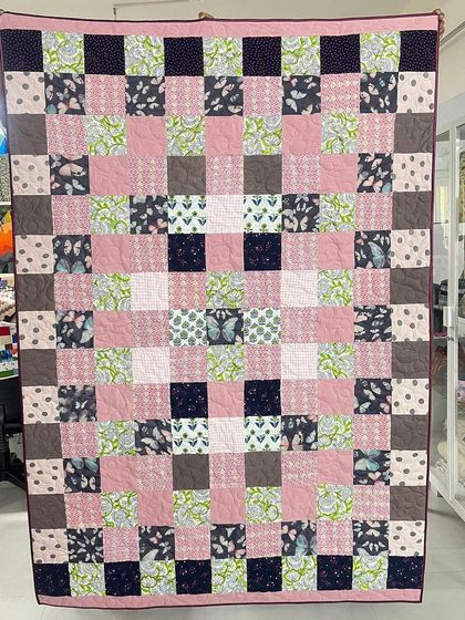 This memory quilt was made for a client from her daughter's frocks and T-shirts. The pink, green, and butterfly-print fabrics are arranged in a cheerful checkerboard pattern.