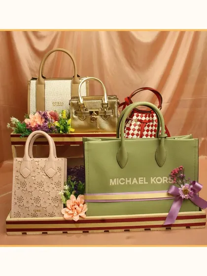 For the fashionista, this trousseau packing idea showcases a collection of luxury handbags from brands like Michael Kors and Guess, displayed on a tiered stand.