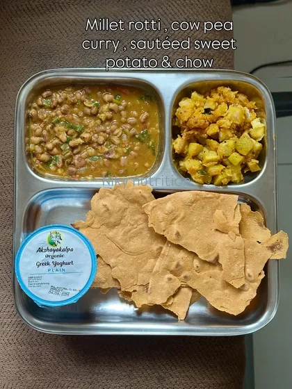 A vegetarian thali with millet roti, cowpea curry, sautéed sweet potato, and Greek yogurt. This meal is high in fiber and rich in plant-based protein.