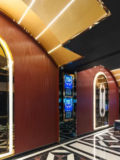 The arched entryways along the main corridor of INOX Jalosa are framed with glowing light, creating a rhythmic and visually engaging journey. The deep red walls and geometric flooring contribute to a cohesive and luxurious design language that runs throughout the megaplex.
