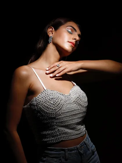 This image uses a single spotlight to create a dramatic, high-contrast effect. The model's pose and the focused light on the beaded top give the shot an intimate and artistic feel.