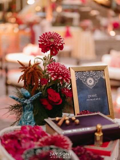 A tabletop vignette from the Mehfil-e-Mehendi, featuring a miniature whirling dervish, a floral arrangement, and an ornate box.