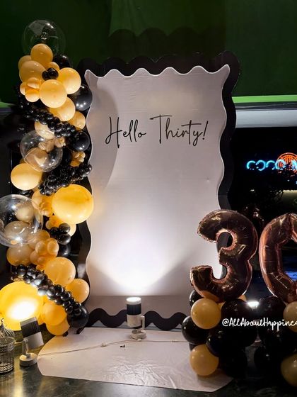 Hello Thirty! We designed this fabulous and flirty backdrop for a 30th birthday, featuring a unique wavy-edged frame and a chic black and gold balloon arrangement.