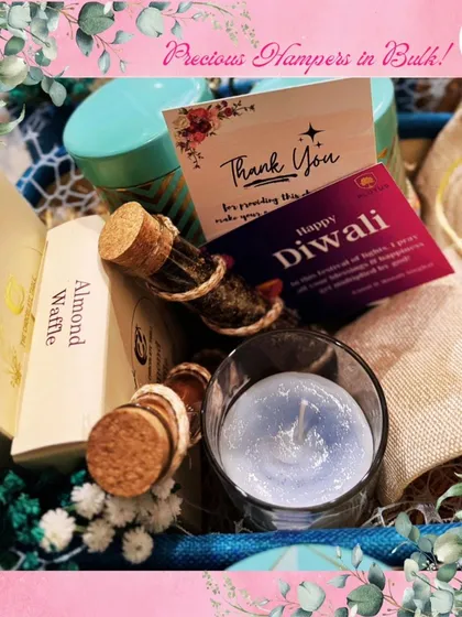A close-up of the thoughtful details inside a festive hamper. This shot shows an almond waffle box, a scented candle, and a "Happy Diwali" card, illustrating the personal touches I add to make each gift special.