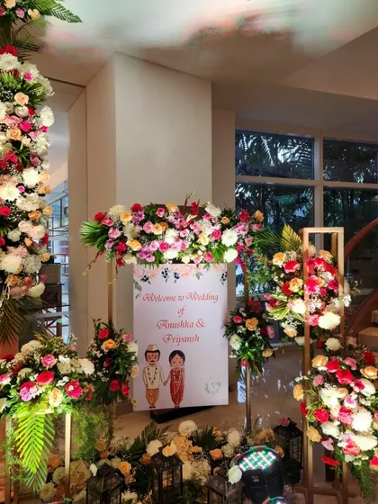 A cute and personalized welcome sign with a couple's caricature, surrounded by vibrant floral arrangements to greet guests with a smile.