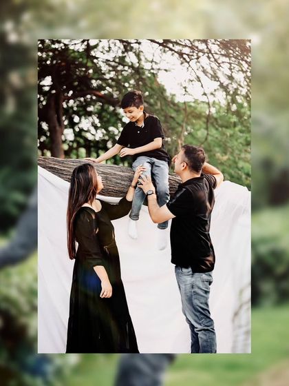 A playful scene from a family photoshoot, where the parents help their son balance on a large tree branch. It's a great example of how we incorporate the natural environment into our sessions.