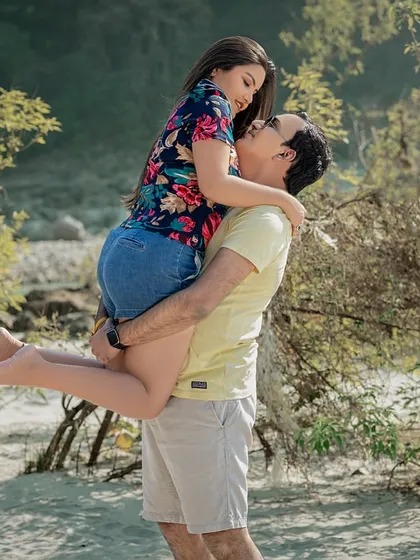 A joyful, playful lift on the sandy riverbank. This candid shot is full of energy and laughter, showing the fun side of the couple's relationship.