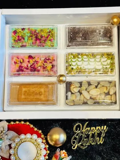 An elegant Rakhi gift box featuring an assortment of our fusion chocolate barks. Flavors include rose pistachio, biscoff, and various nut and seed combinations.